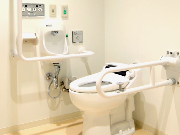 個室内に緊急コールのボタンと紐を設置して、安全性を高めている。白を基調とした清潔感がある内装のトイレである。