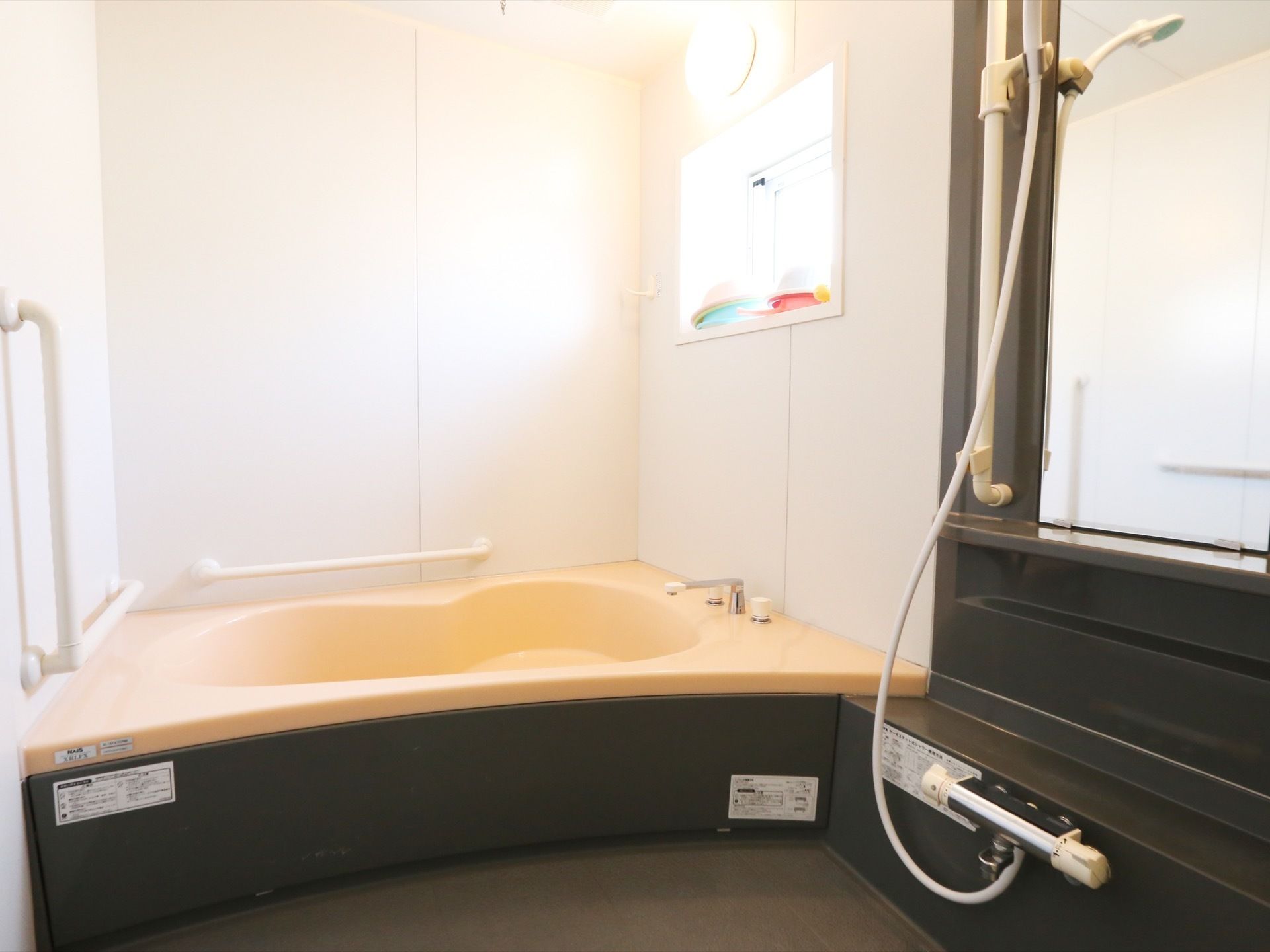 スタイリッシュな一般浴室である。壁には、手すりが設置されている。換気に利用できる窓が設けられている。