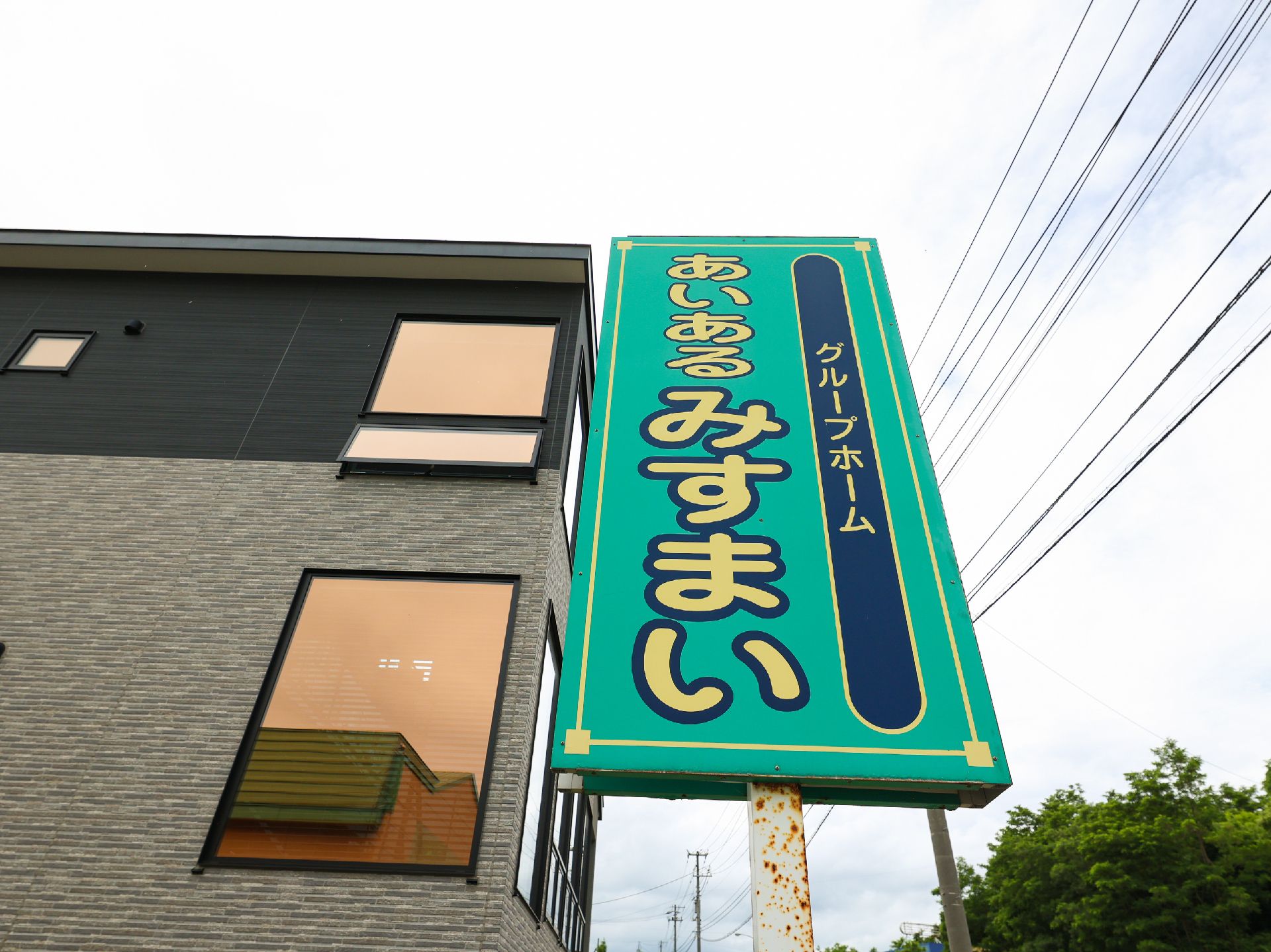 黒と灰色の外観の建物の側面につけられた緑色の看板