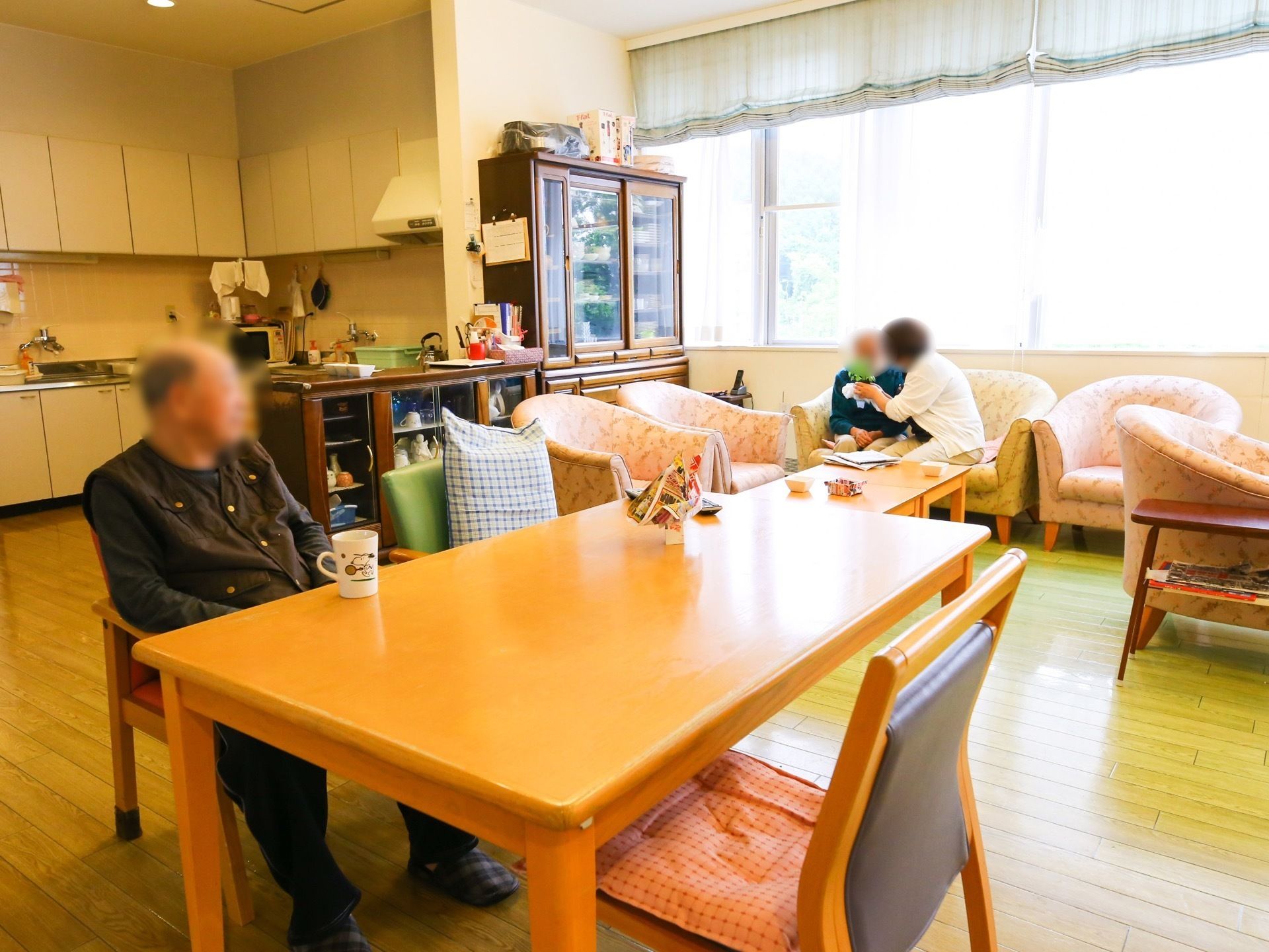 窓前にはソファーが並べられ、その前にテーブルが置いてある。椅子の上には、クッションや座布団が用意されている。