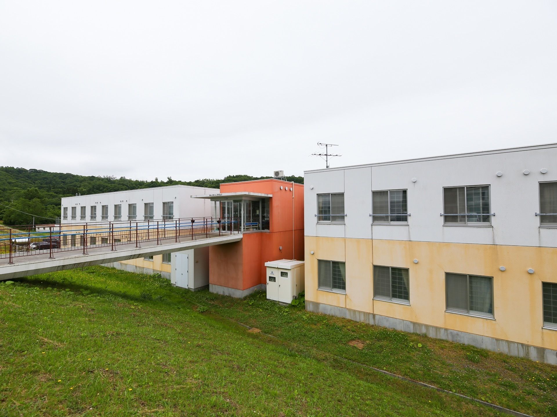 2階建てで、白と黄色に塗られた建物の間に、オレンジ色の建物がある。オレンジ色の建物の２階は、そのまま外まで通路で繋がっている。
