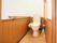 便座の左側にI字、右側にL字の手すりが取り付けられている。トイレの隅には、水色の掃除道具が置いてある。