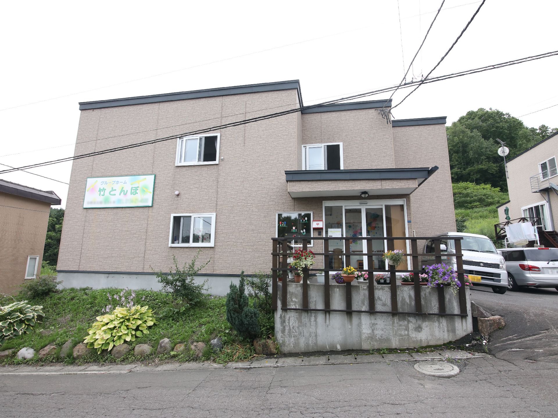 日当たりのいい屋外で散歩を楽しんでいる白髪の高齢女性と付き添いの若い女性スタッフ。
