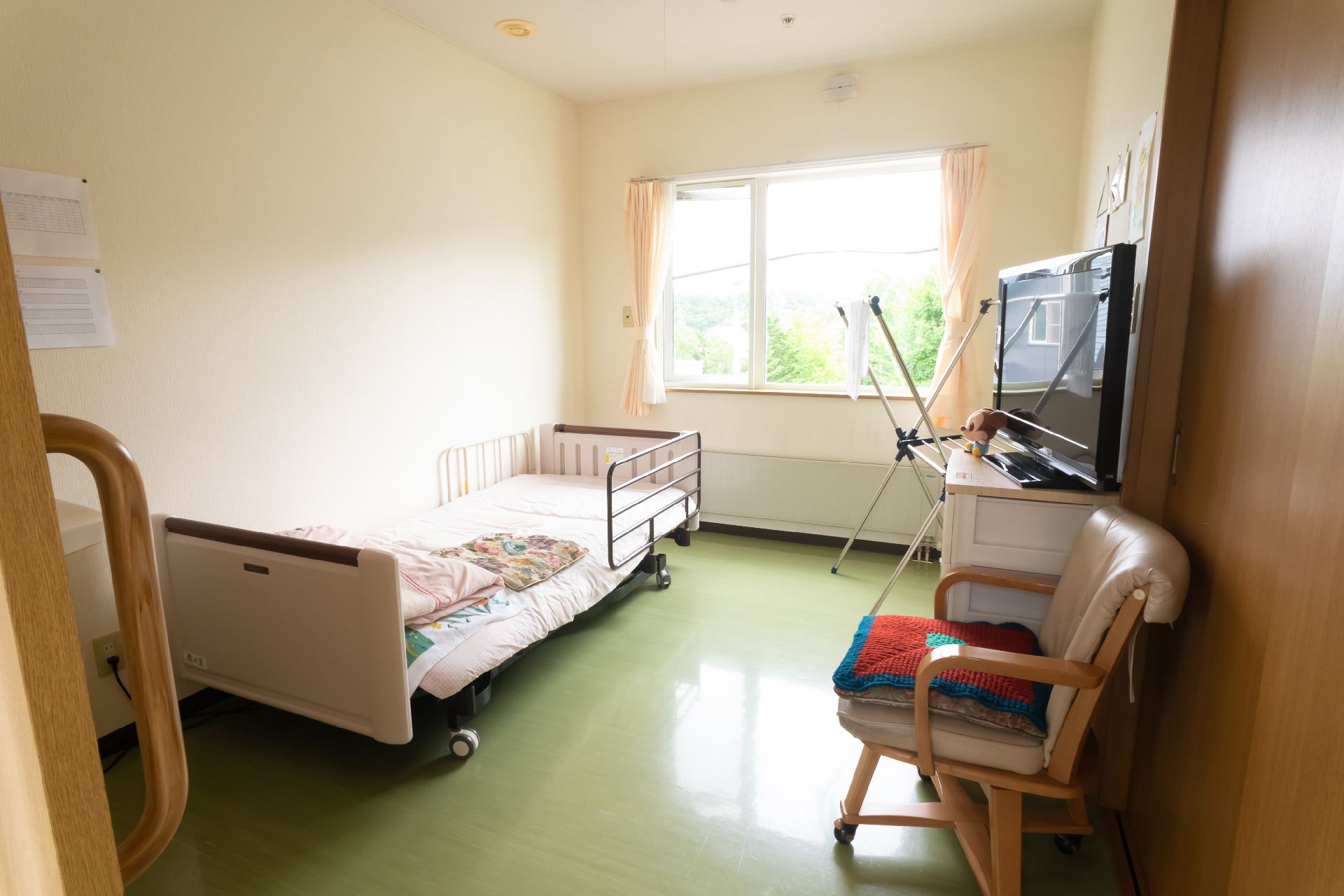 窓から日差しが入り、介護ベッドやテレビ、椅子などが置かれている居室