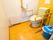 木製の手すりに囲まれた洋式便器がある黄色と白の壁の部屋