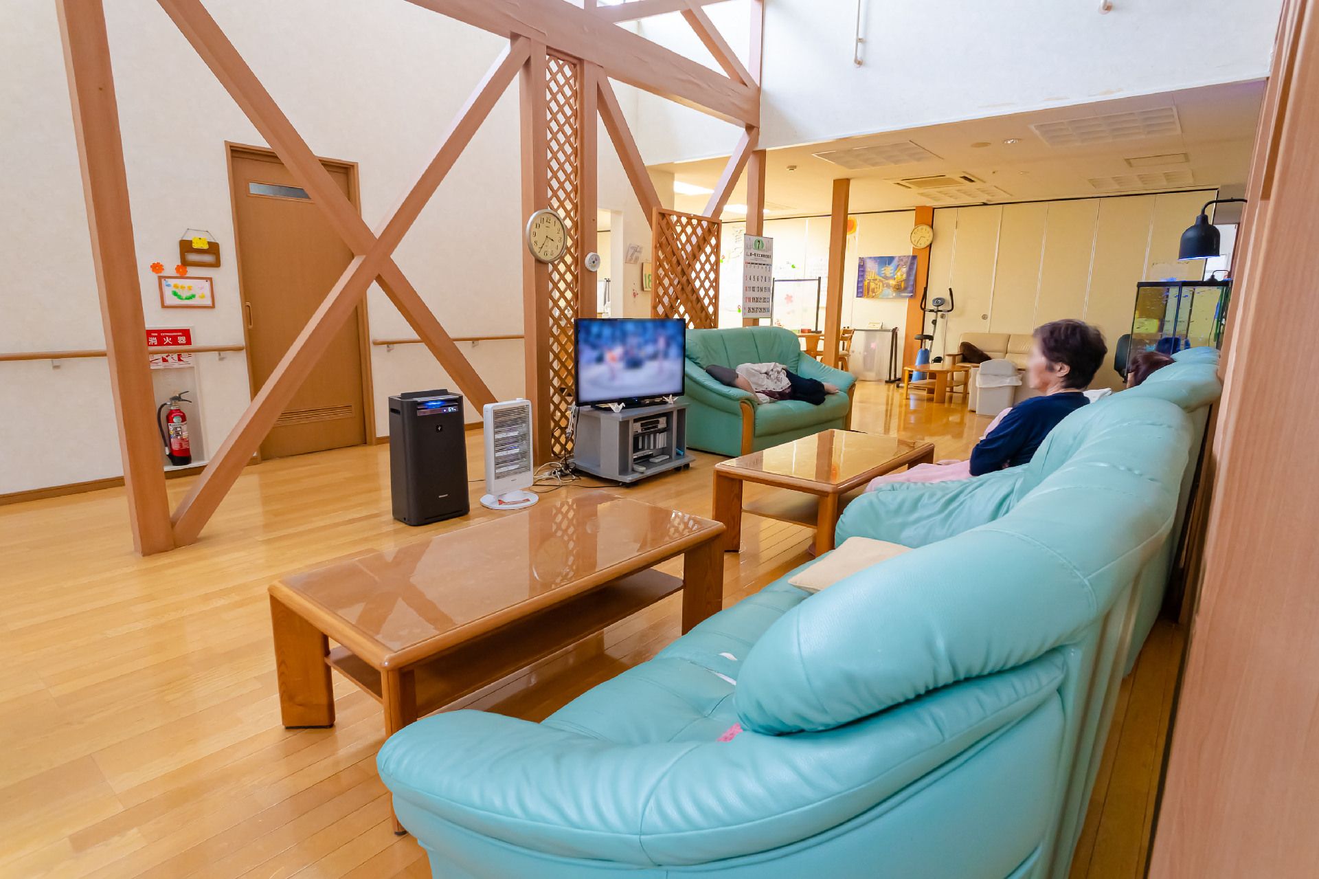 テレビを青色のソファーに座りながら見ている入居者様