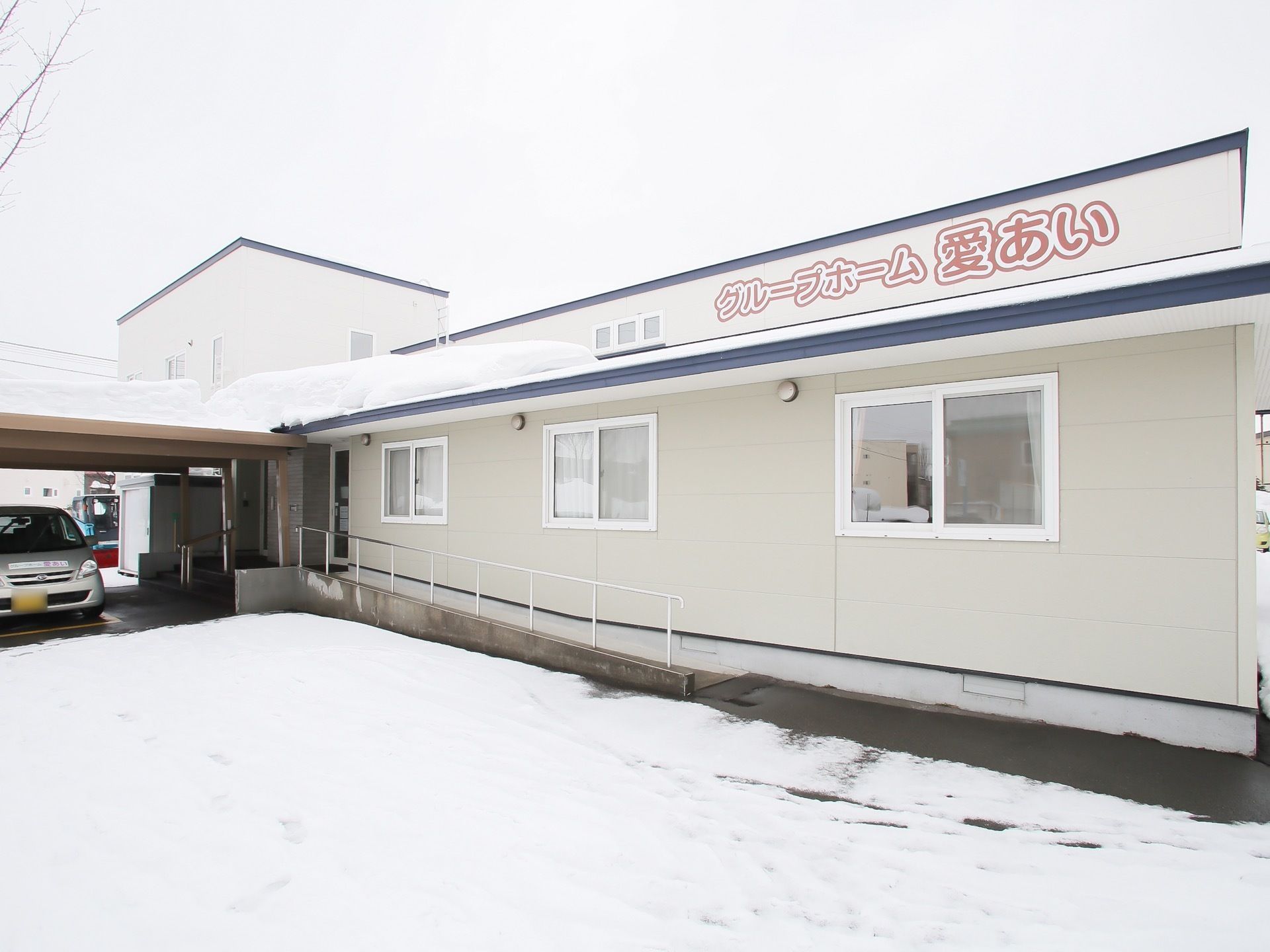 施設は２階建ての建物である。エントランスに車寄せが設けられており、手すりが備わったスロープが設置されている。