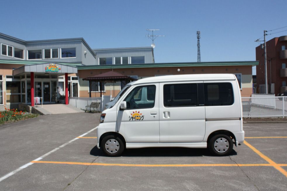 スロープ付きの厳顔と手前に施設用の車が写っている施設の全景
