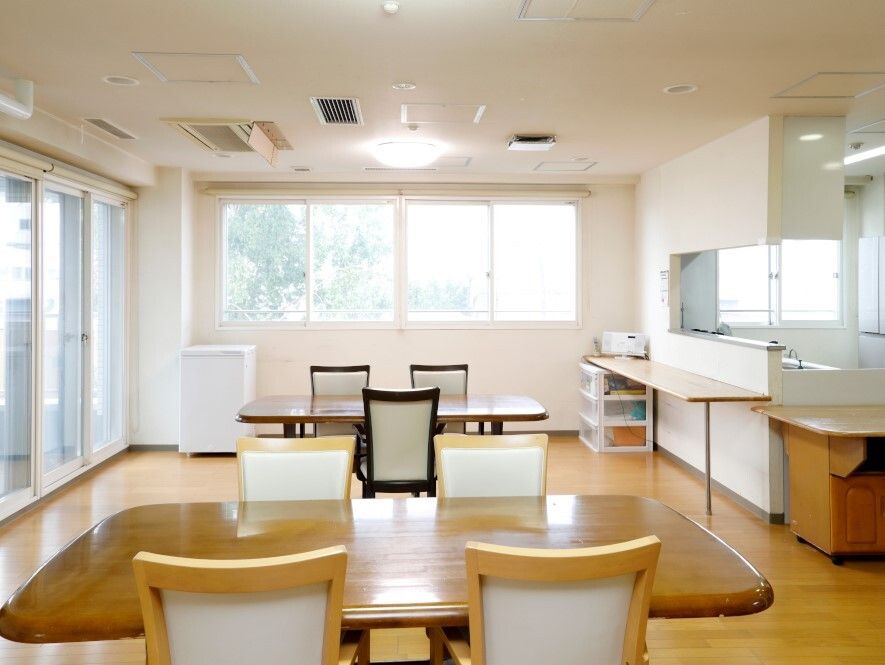 大きな窓が付いたリビングダイニングには木製のテーブルセットが置かれ、対面式のキッチンが設置されている。
