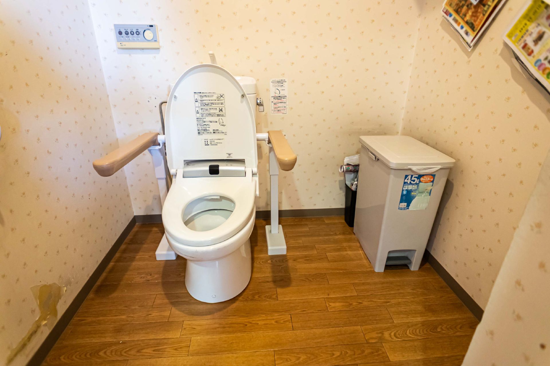 肘掛け付きの洋式便器を備えたトイレ