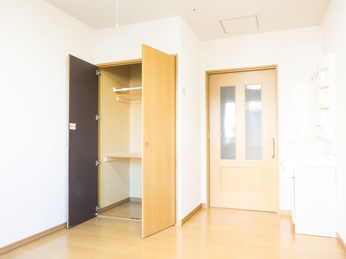 収納設備が付いているワンルームタイプの部屋の様子。木製の床とドアが写っている