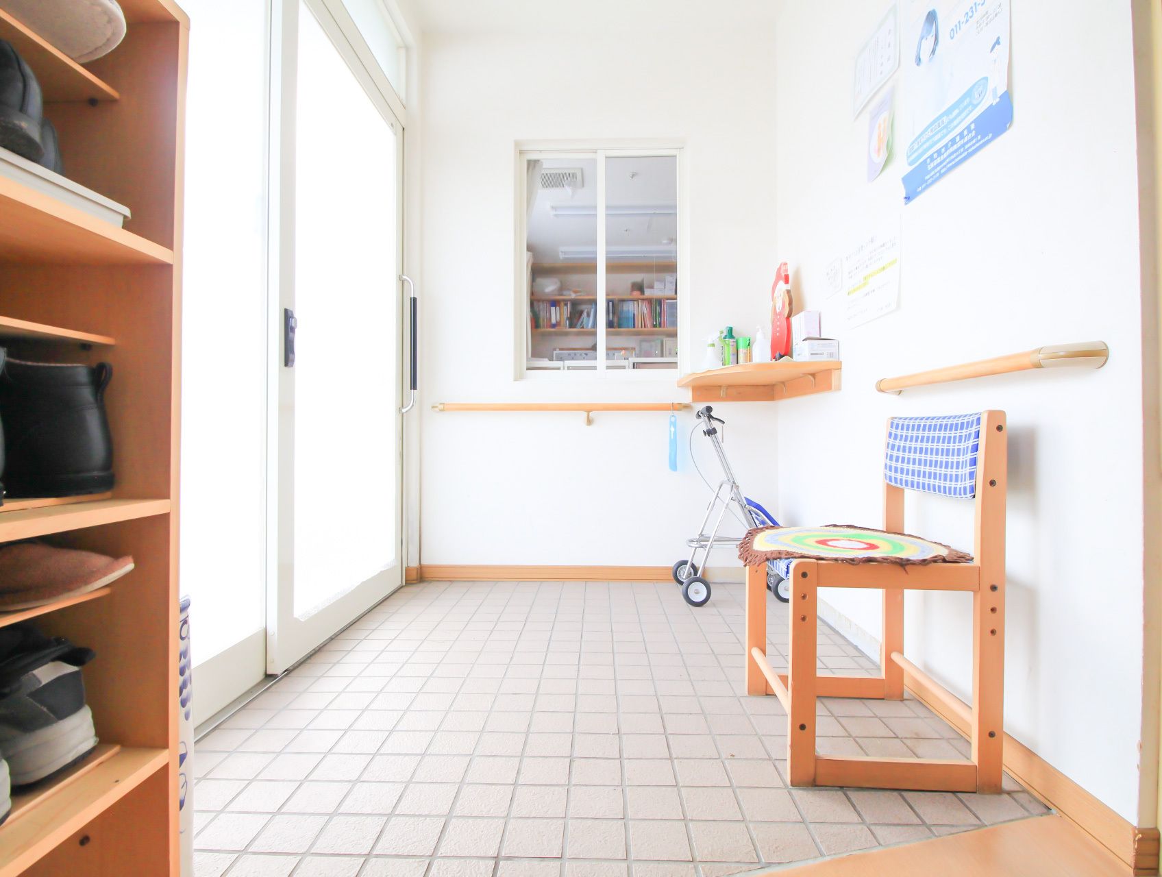 大きなドアで、椅子や歩行器具が置かれているフラットな床の玄関