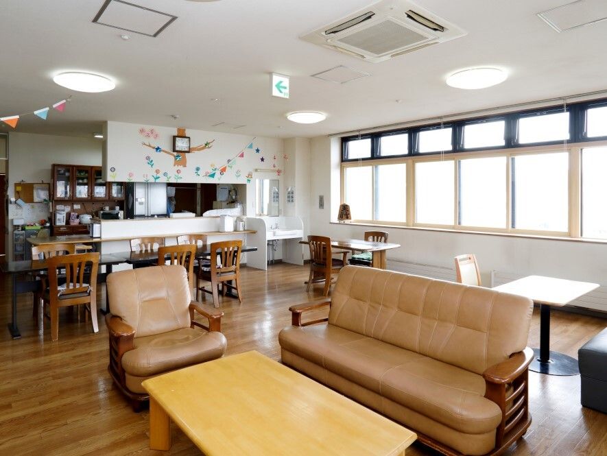 大きな窓が付いた明るい雰囲気のリビングダイニング。ソファの応接セットやダイニングテーブルがあり、キッチンは対面式。