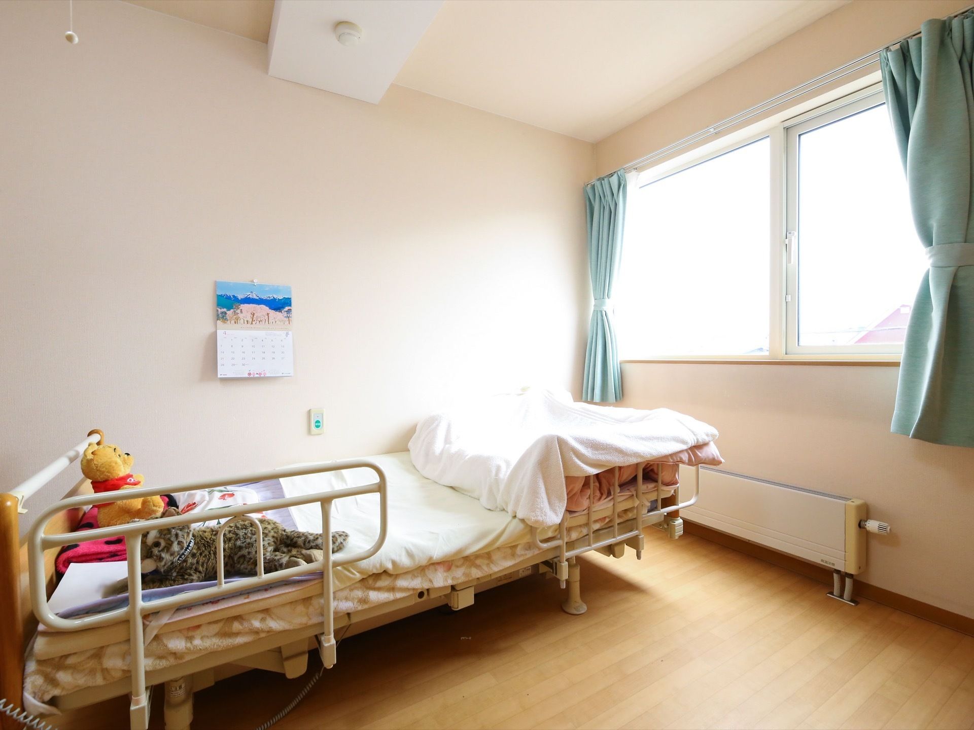 居室の窓は、横広であり明るい自然光を取り込むことができる。壁には緊急時に用いる緑のボタンがついており、近くにベッドを設置している。
