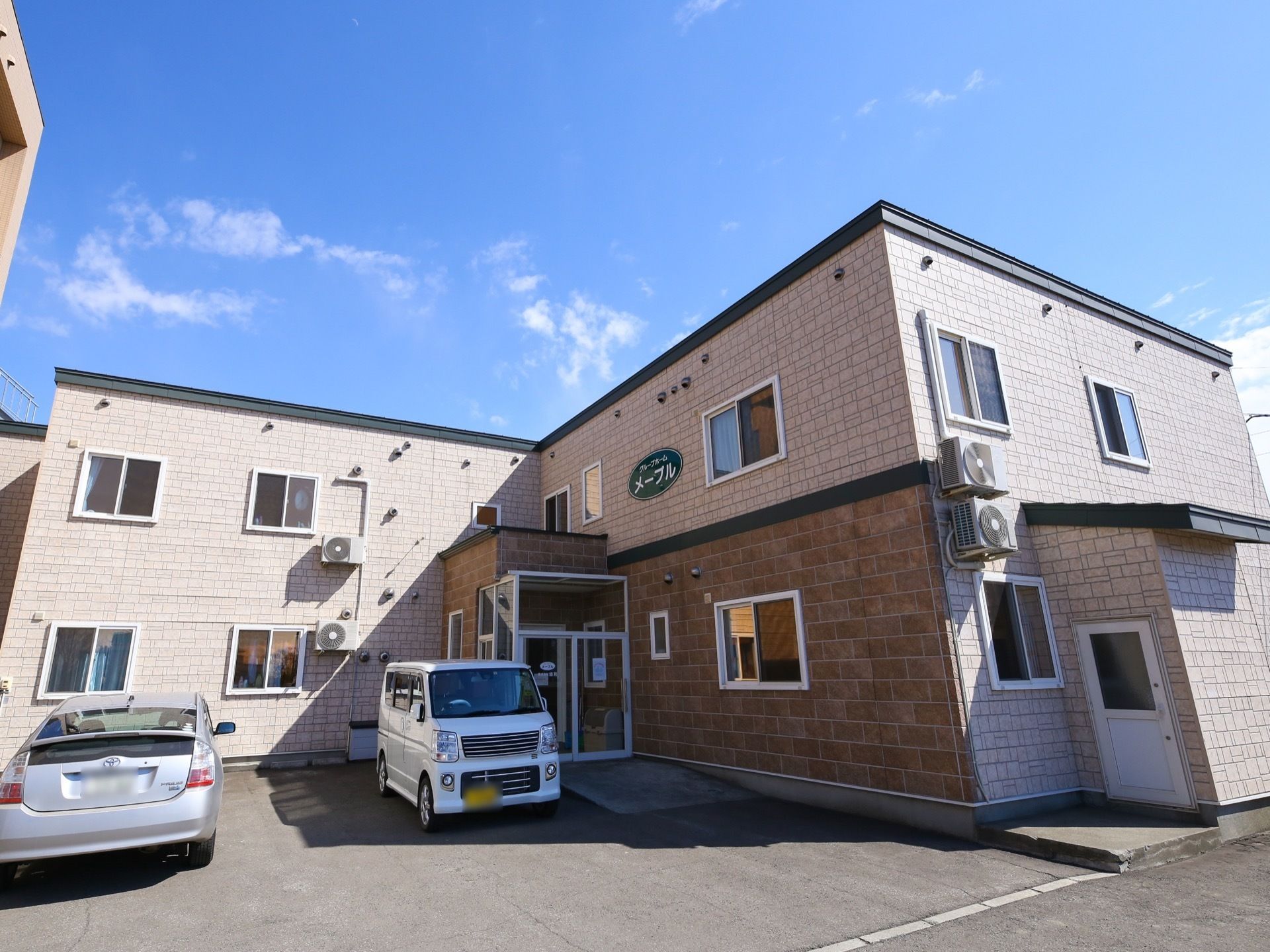 明るい色調の外観で柔らかい印象のある外観。一見すると２階建ての集合住宅のような造りで、Ｌ字型に建てられている。