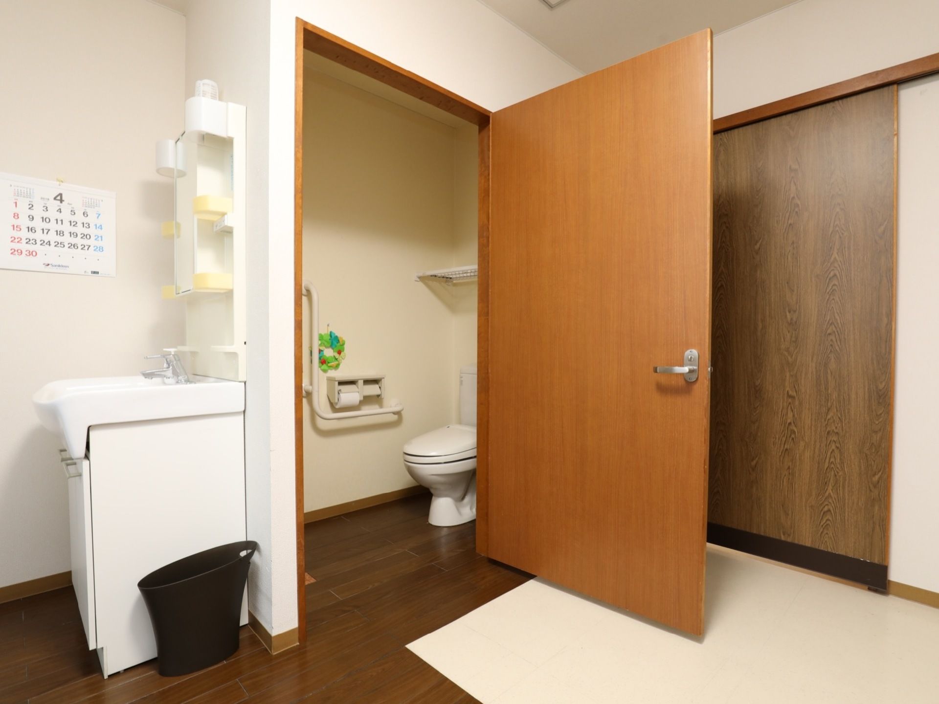 収納スペースと鏡付きの洗面台が備え付けられた居室。入口近くの扉を開けるとトイレがある。段差のないフラットな床である。