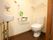 広々としたトイレ内。便座の上にはつっぱり棒で収納スペースが確保されている。また安全のために壁に手すりが備えられている。