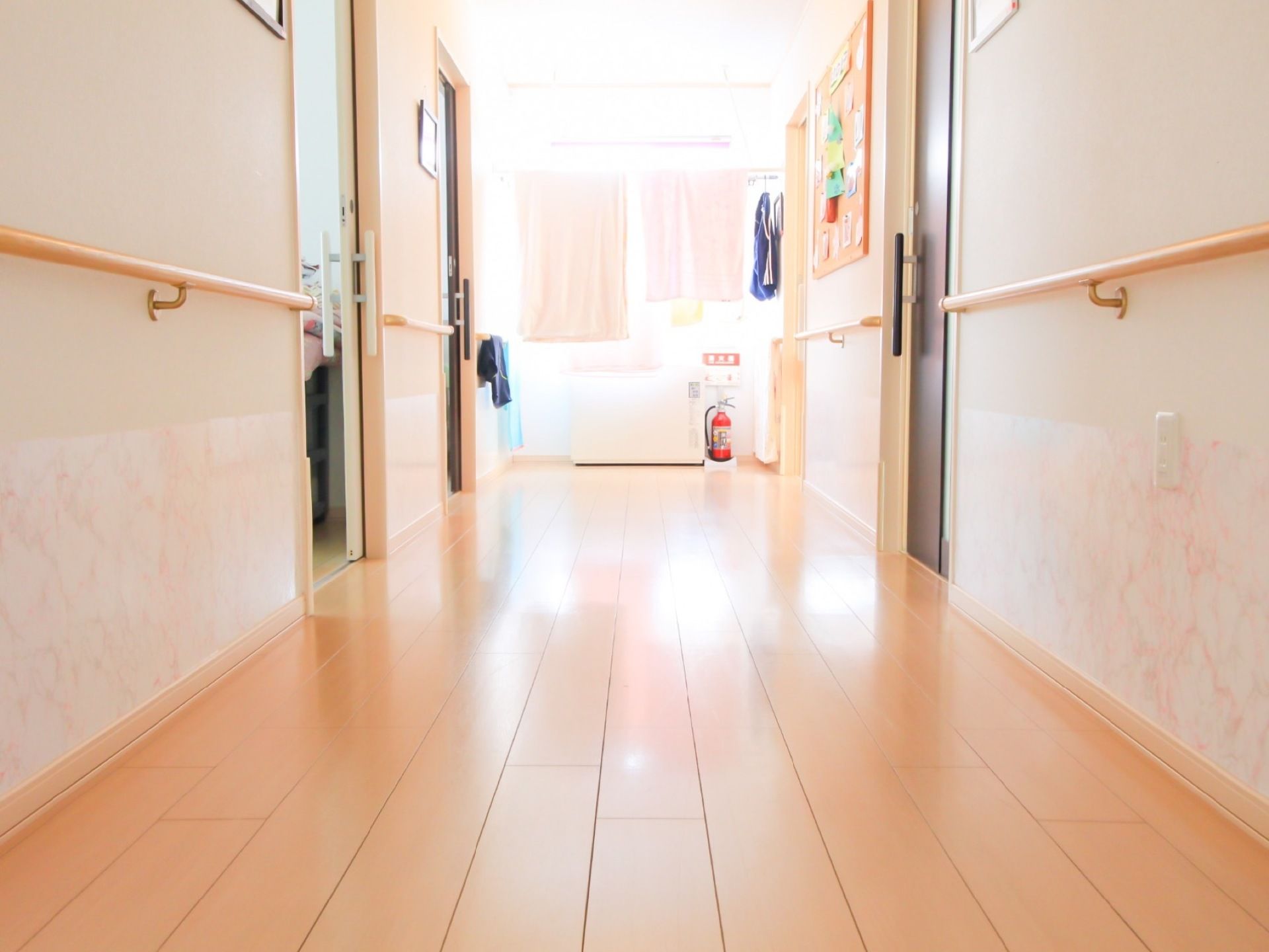 施設内の通路はフローリングで、足元に段差がない。壁には手すりが付けられている壁の下の方は、華やかな壁紙となっている。
