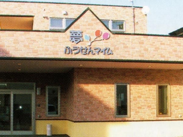 2階建ての建物は明るいブラウンのレンガ調の外壁で、外壁にはホーム名と風船があり、日当たりもよい。