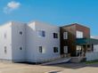 ライトグレーとブラウンの2階建ての建物の玄関には手すり付きのスロープがあり、屋根も付いている。