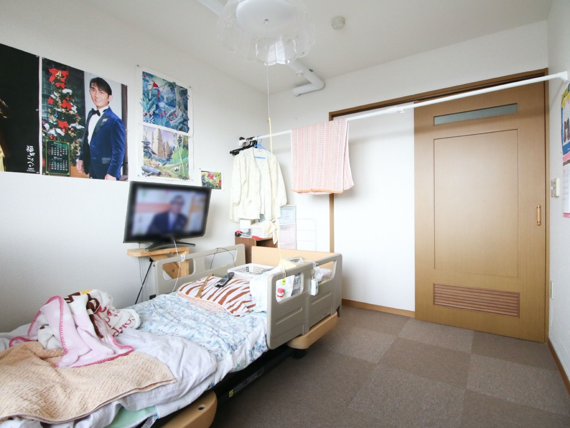ライトブラウンの引き戸には、上の方に細長いすりガラスがはめ込まれている。ポスターカレンダーが、左側の壁に貼ってある。