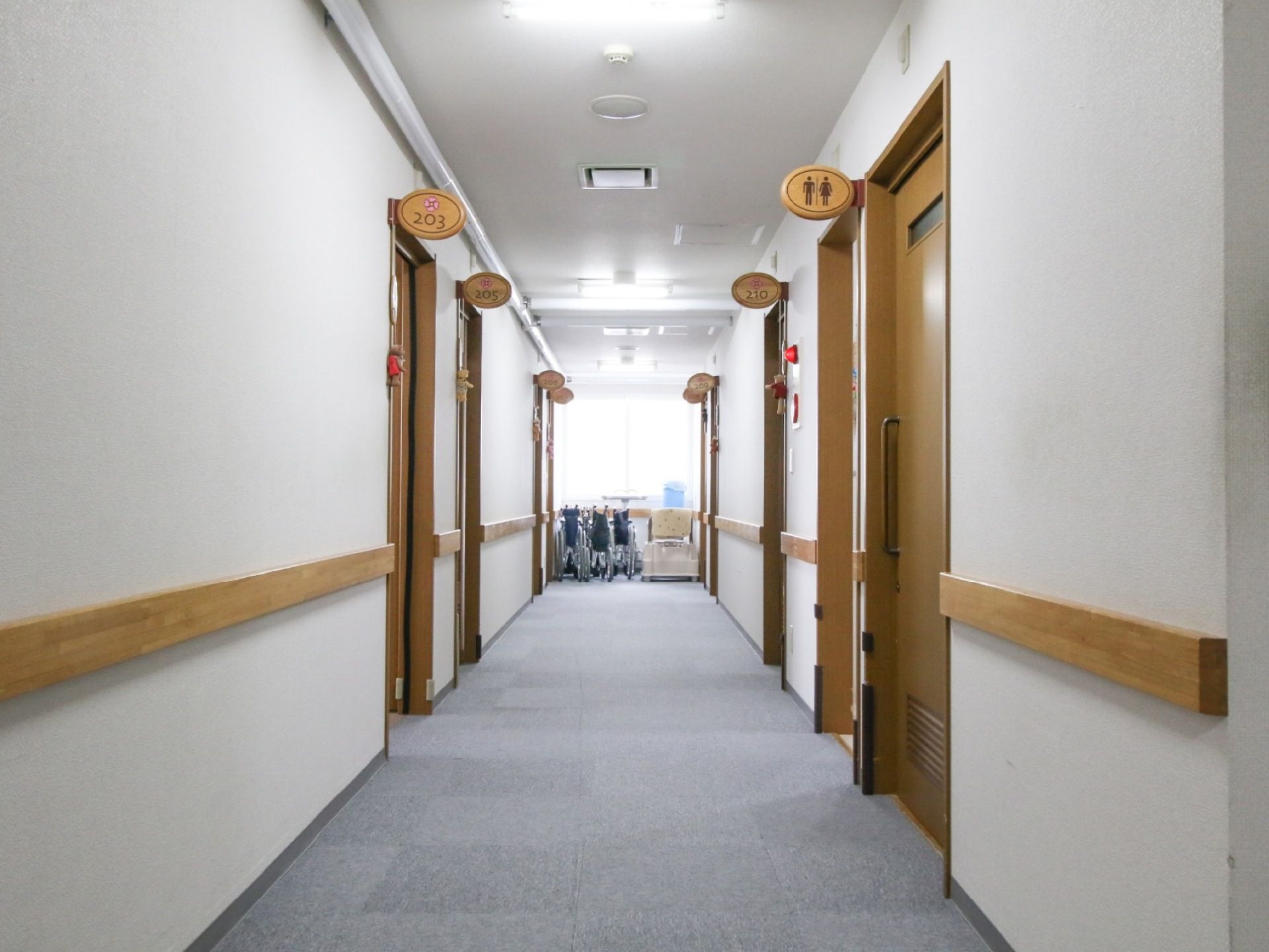 両側の壁に、幅の広い木製の手すりが取り付けられている。部屋番号が印字されたプレートに、ぬいぐるみが吊り下げてある。