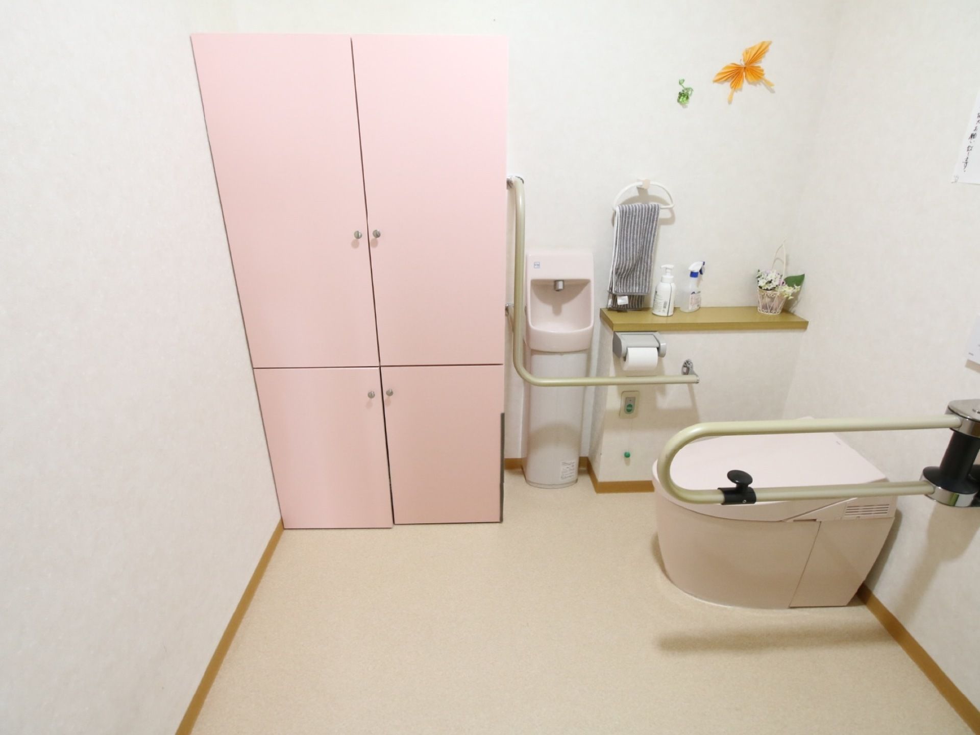 広いスペースが確保されたトイレである。緑色の緊急時用コールボタンが、トイレットペーパーホルダーの下にがある。
