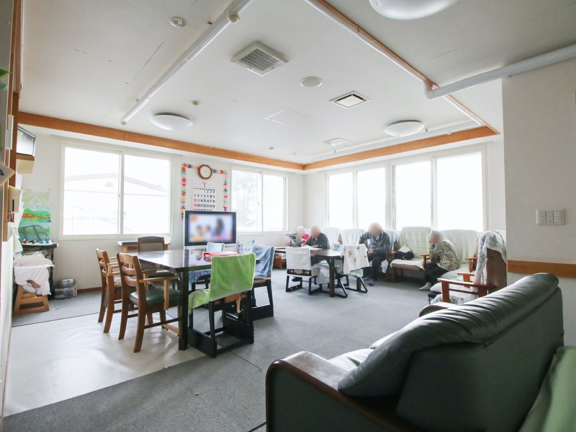 テーブルセットやソファがいくつもある、テレビも置かれている食堂