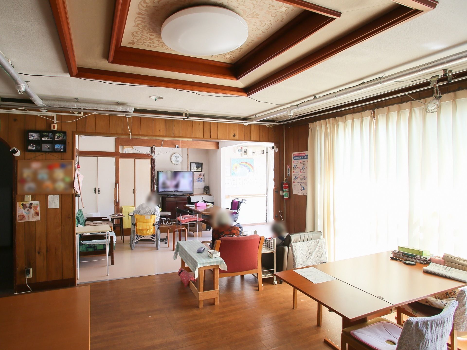 室内は日当たりが良く広々としている。中央にテーブルや椅子が置かれ、テレビが視聴しやすいように配置されている。