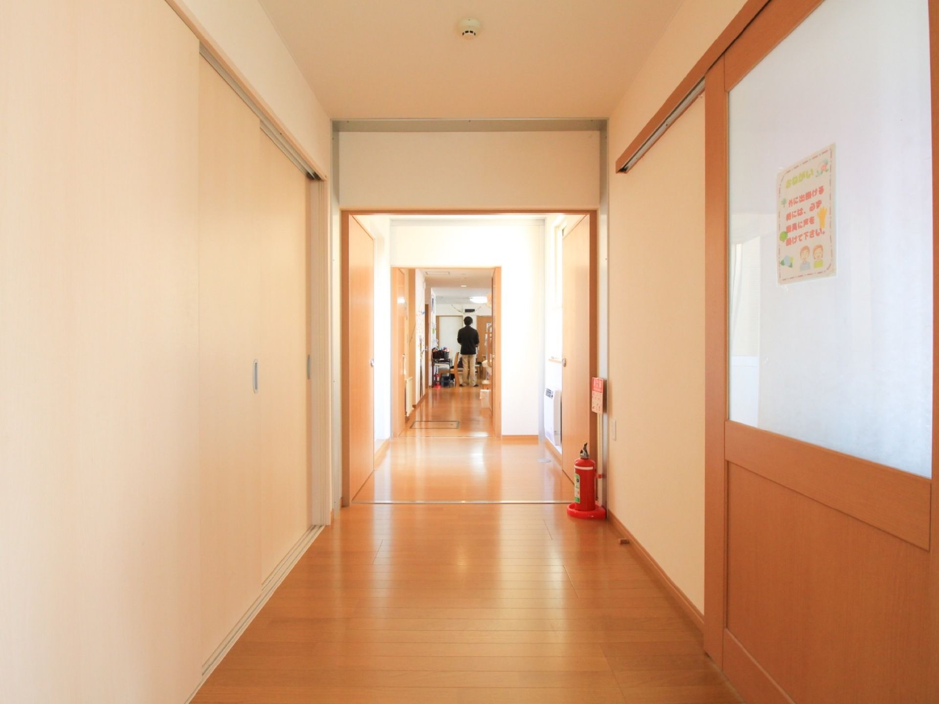 通路の床は、明るいナチュラルカラーのフローリング材を使用している。各部屋の扉はスライド式で、扉のサイズが大きい。