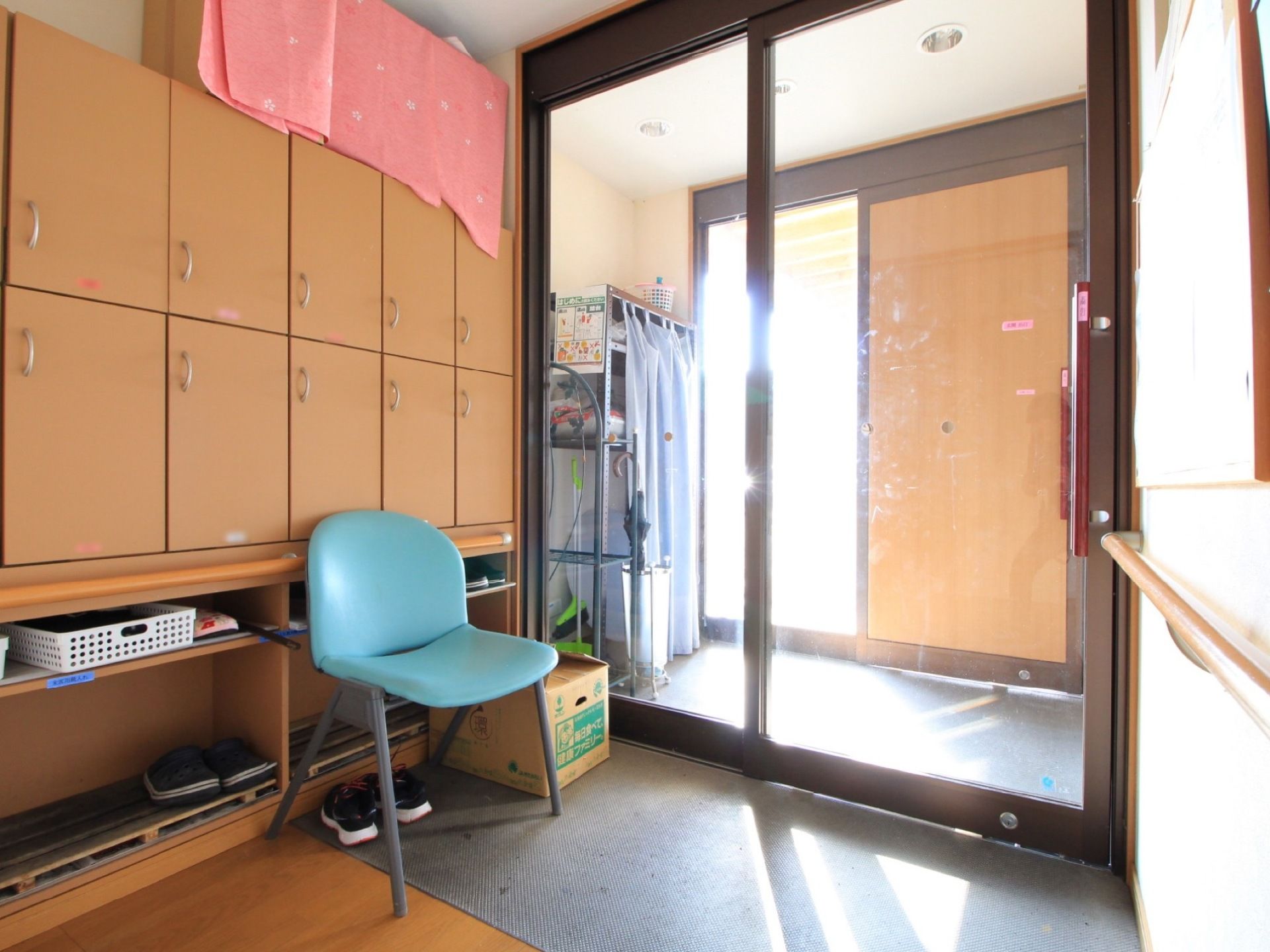 玄関には風除室がある。ドアはスライド式。建物に入ってすぐの場所に手すりが取り付けられている。下駄箱の前には椅子が置かれている。