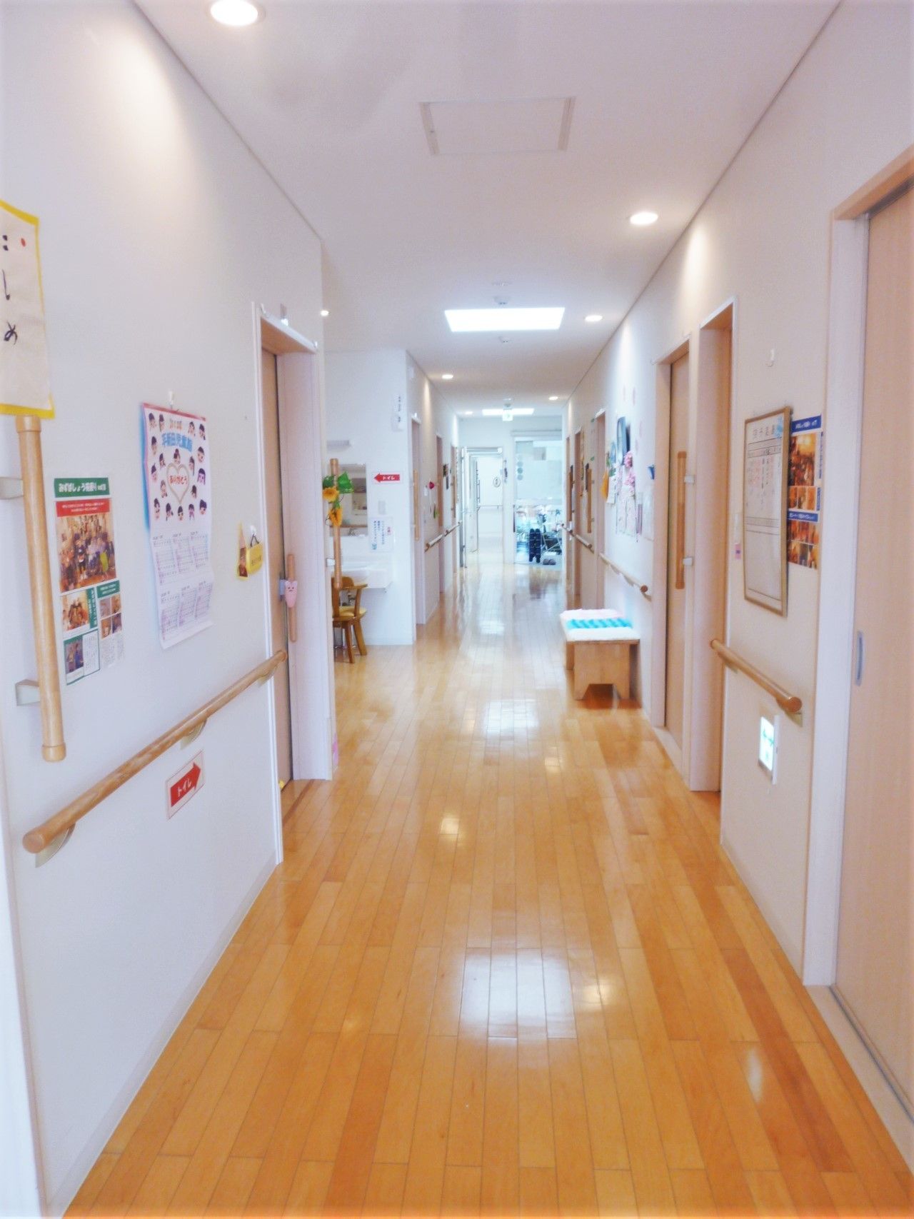 壁に手すりがついた施設内の廊下の様子。両側に個室やスタッフステーションがある