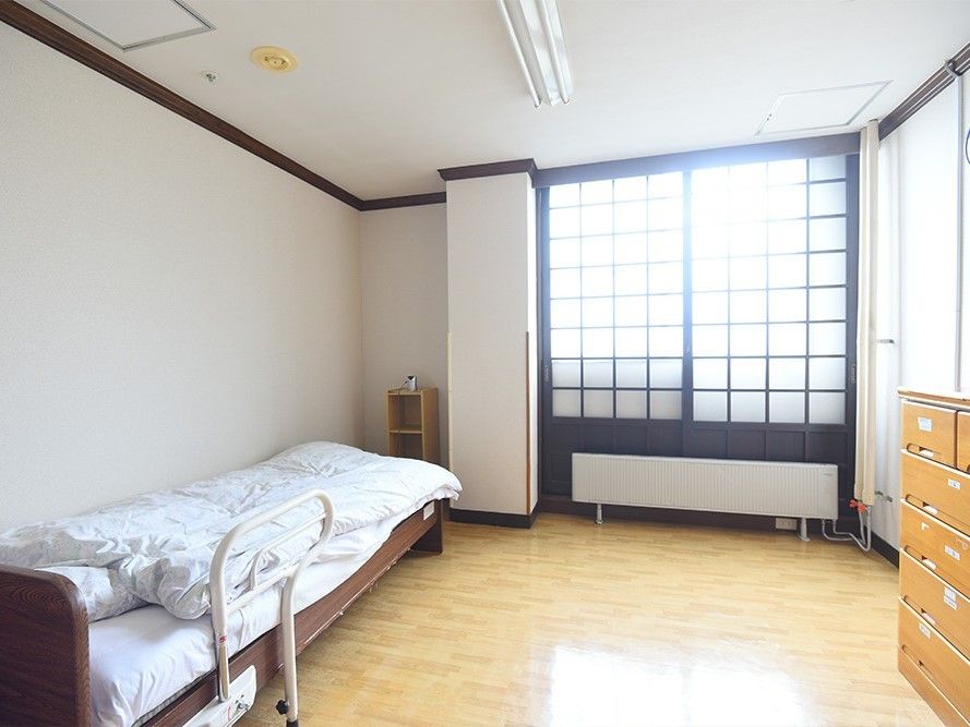 日当たりがよく明るい居室にはベッドやタンスが置かれている。フローリングの部屋。
