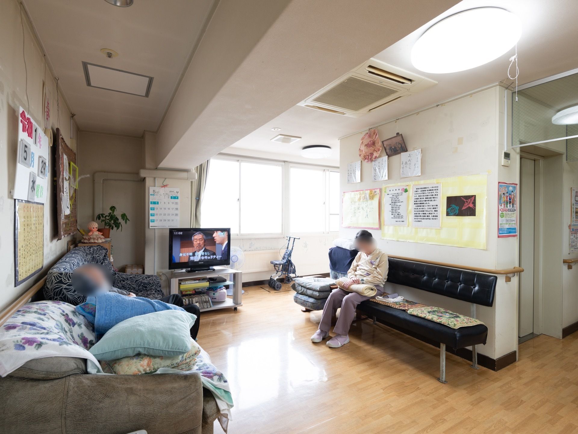 正面の窓からは明るい光が入り、開放的な空間である。中央奥にはテレビがあり、左右の壁際にはそれぞれソファーと長椅子が設置されている。