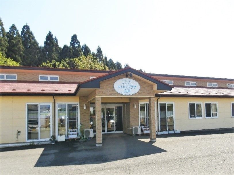 平屋建ての建物の玄関先には車寄せが付き、建物の後ろには緑が広がっている。