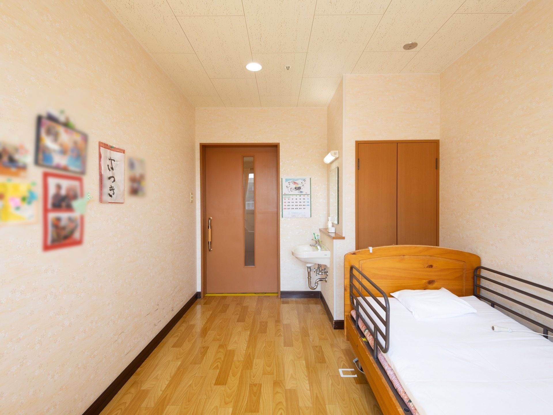 居室の入口は、縦長のスリットが入った引き戸である。転落防止柵つきのベッドが設置されている。入口付近に洗面台がある。
