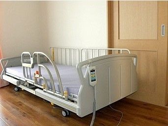 介護用ベッドが置いてある小さなワンルームタイプの部屋。何も置いていない入居前の部屋の様子