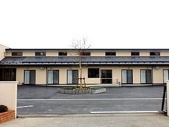 大きなコーポのような雰囲気の建夫野の外観。手前に駐車場スペースがある広めの敷地内