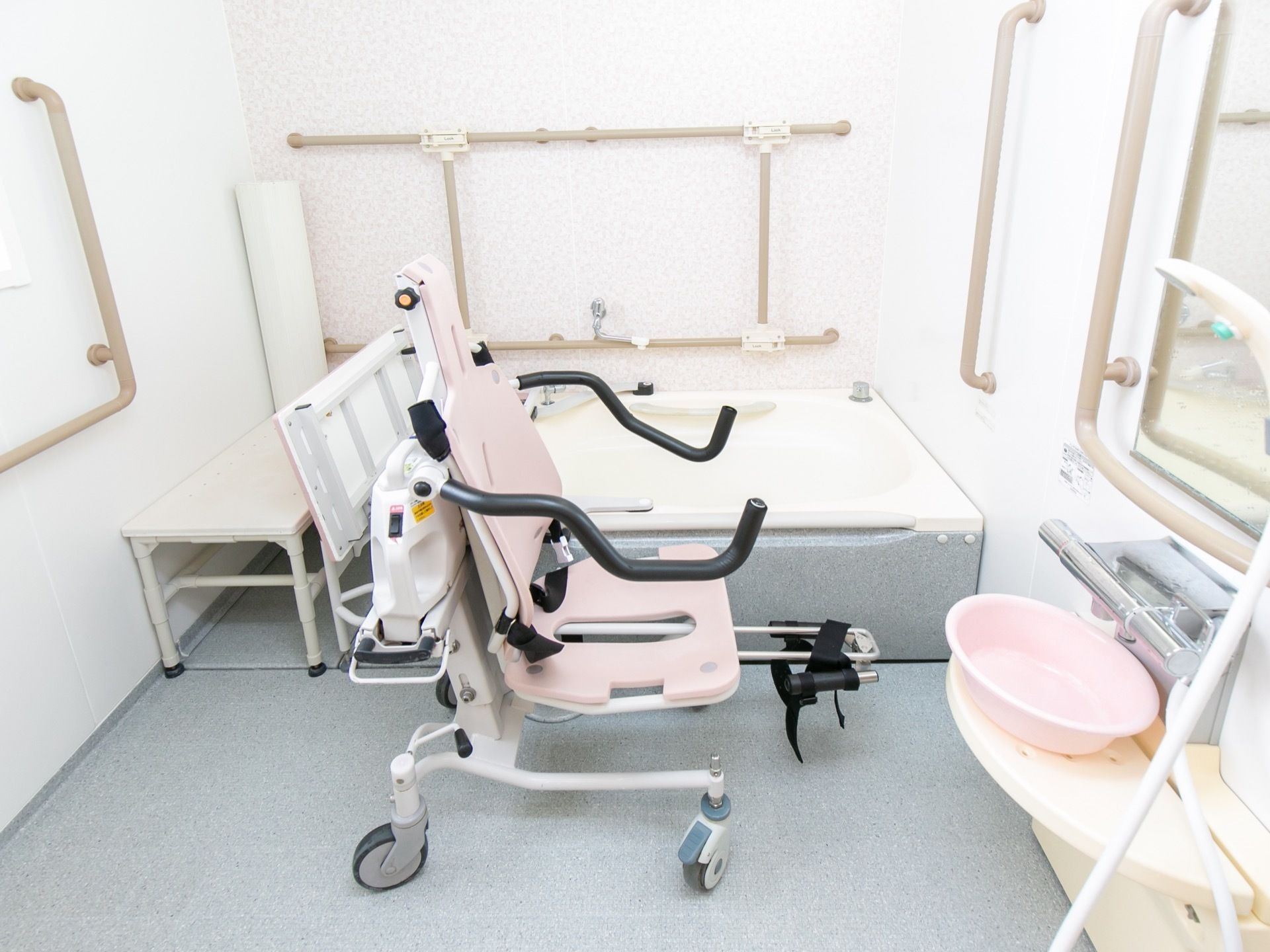 浴室には専用の車椅子を用意している。浴槽も可動式で、入浴時に体を乗せるための台もある。壁の要所には手すりも設置されている。
