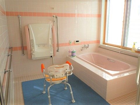 手すりとシャワーチェアがある施設内の浴室。家庭用サイズに近い浴室の様子