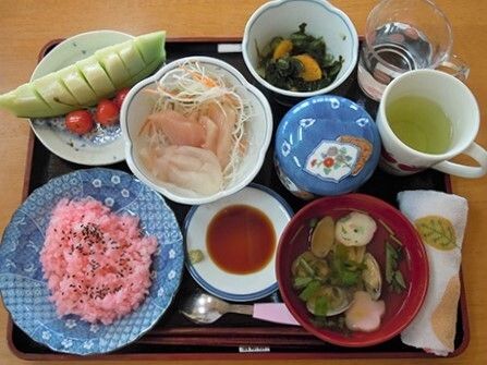 桜色のご飯やお吸い物、その他のおかず類が並べられている施設内のメニュー例
