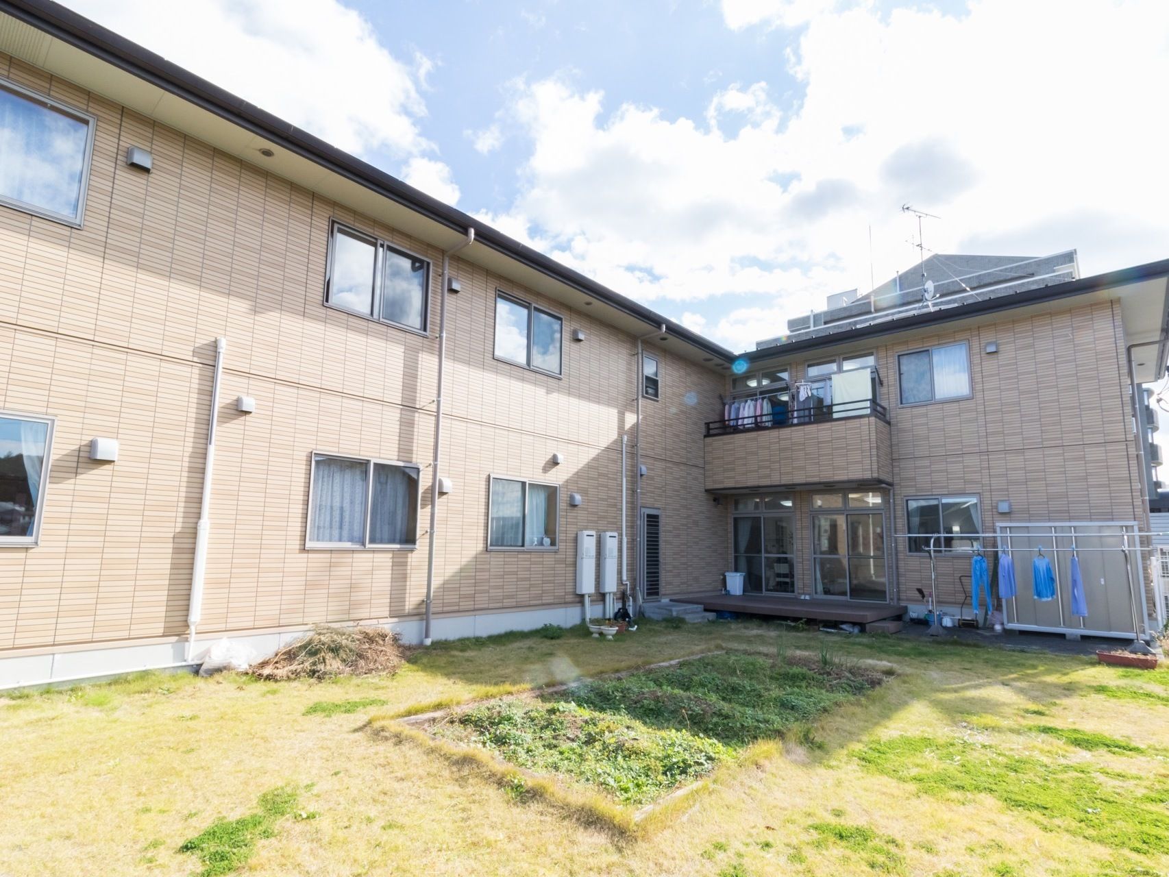 施設の目の前には土の庭があり、その中央には畑が作られている。建物の側には、洗濯物を干すスペースが用意されている。