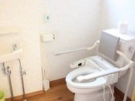 立ち上がり用の手すり後洗面台があるトイレ。施設内の高齢者向けトイレの写真