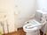 立ち上がり用の手すり後洗面台があるトイレ。施設内の高齢者向けトイレの写真