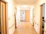 まっすぐな老化の両側に個室のドアがある様子。手すりが取り付けられている廊下