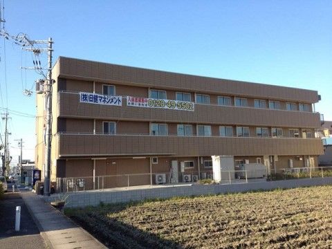 外壁は薄い茶色で統一され、ベランダを備えた３階建て施設の外観