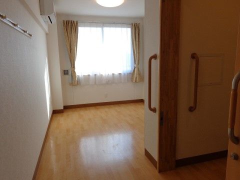 腰高の窓にレースカーテンがかかっている、エアコン完備の居室