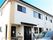 2階建ての建物は白をメインとしていて、玄関には屋根が付き、ベンチも置かれている。