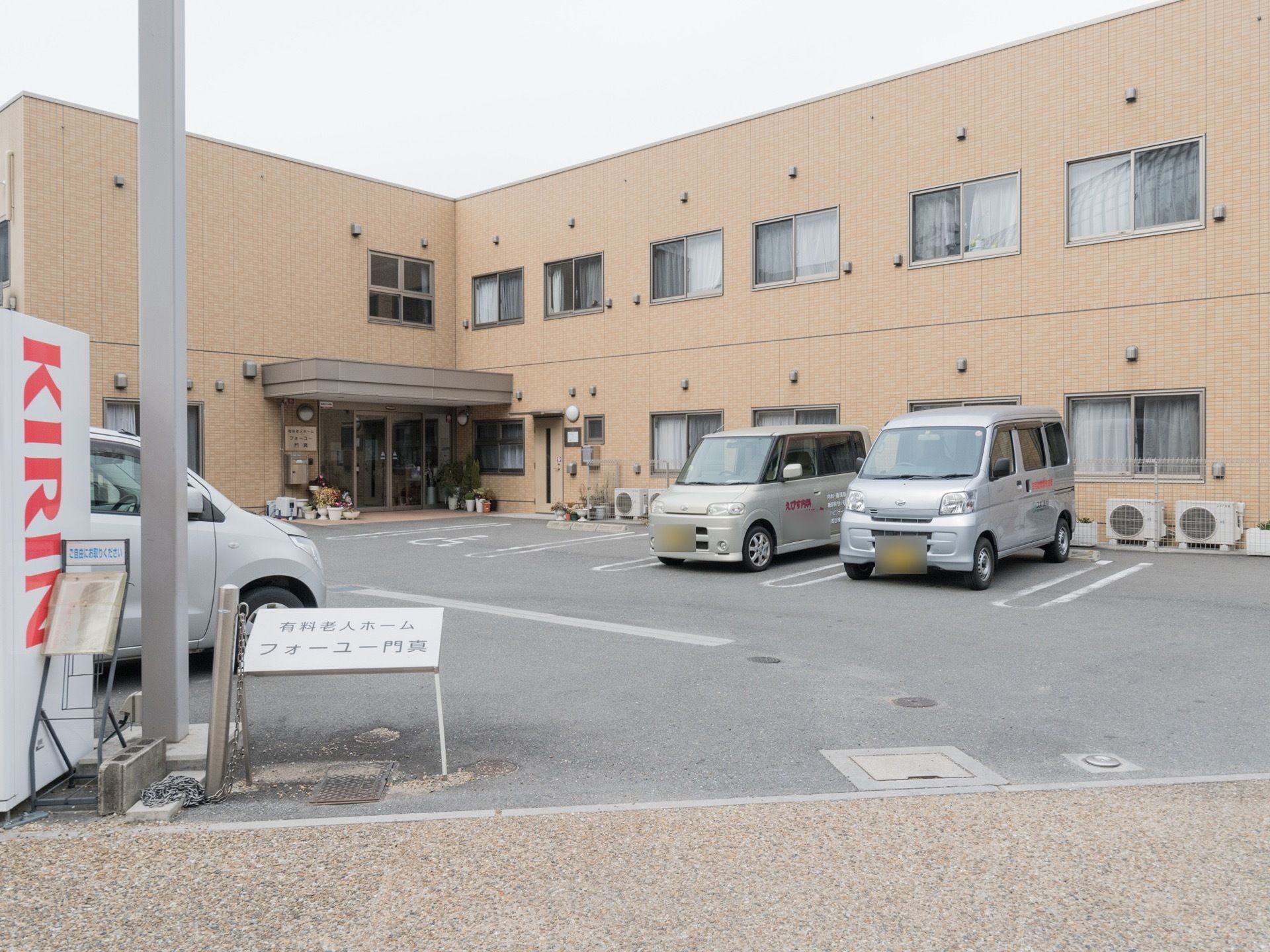 壁がベージュ色の２階建ての建物である。敷地内に入ってすぐ左に施設名が書かれた小さな看板が立っている。駐車場が完備されている。
