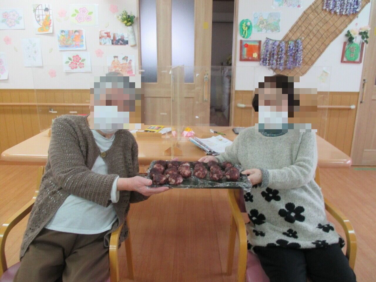 笑顔で手作り菓子を見せる居室